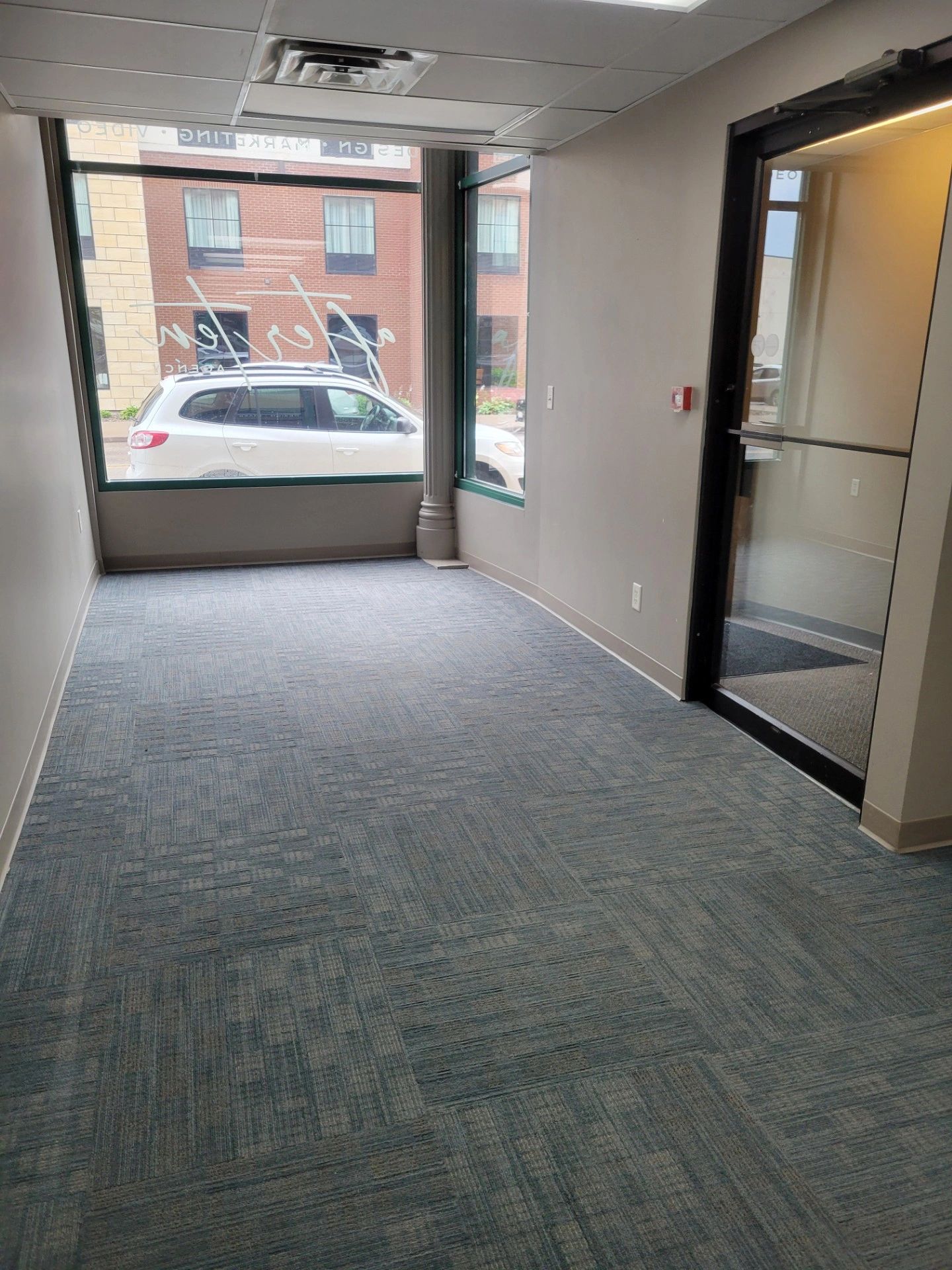 Empty office space with large window and glass door.