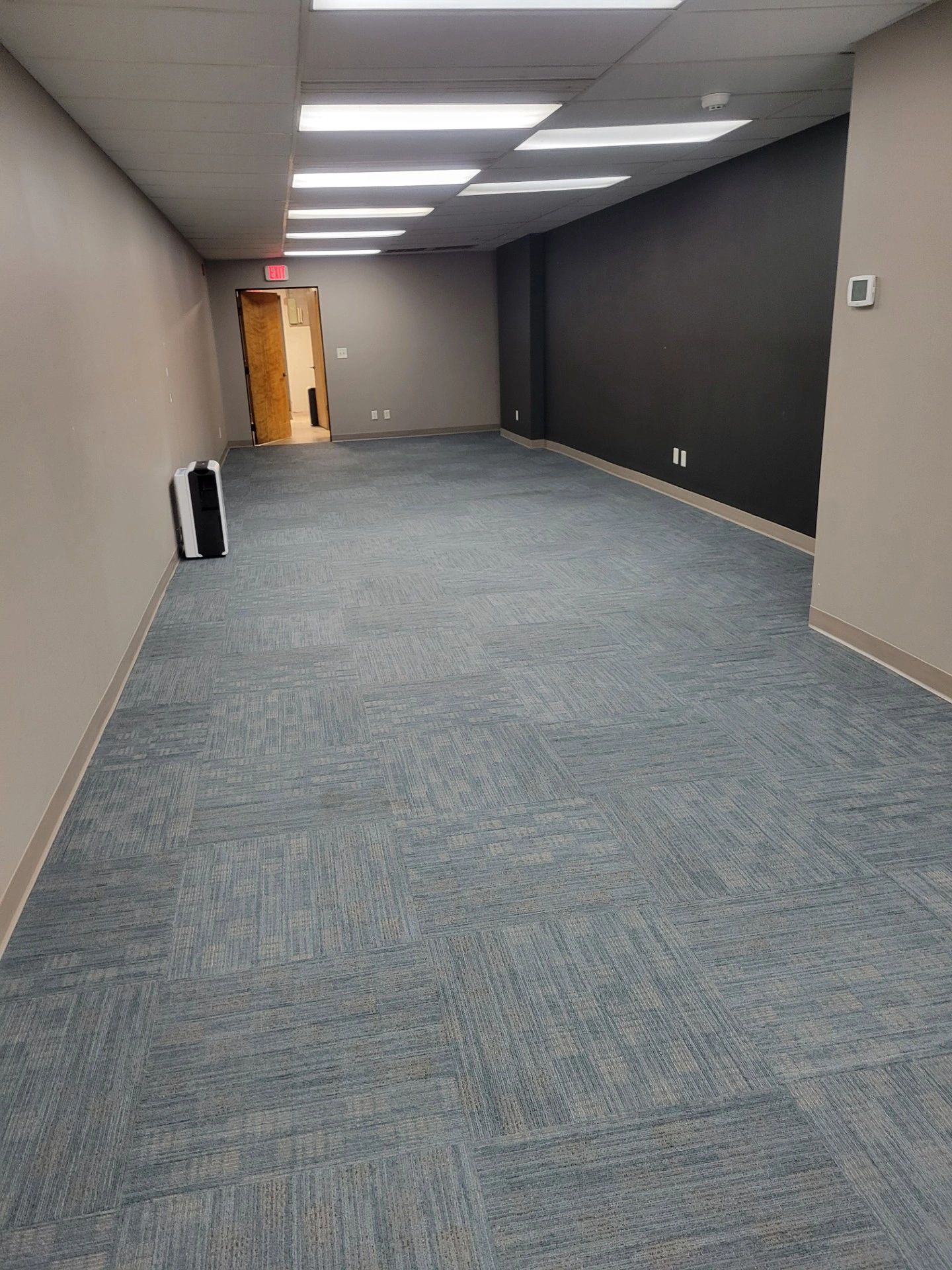 Empty office room with carpet and fluorescent lights.