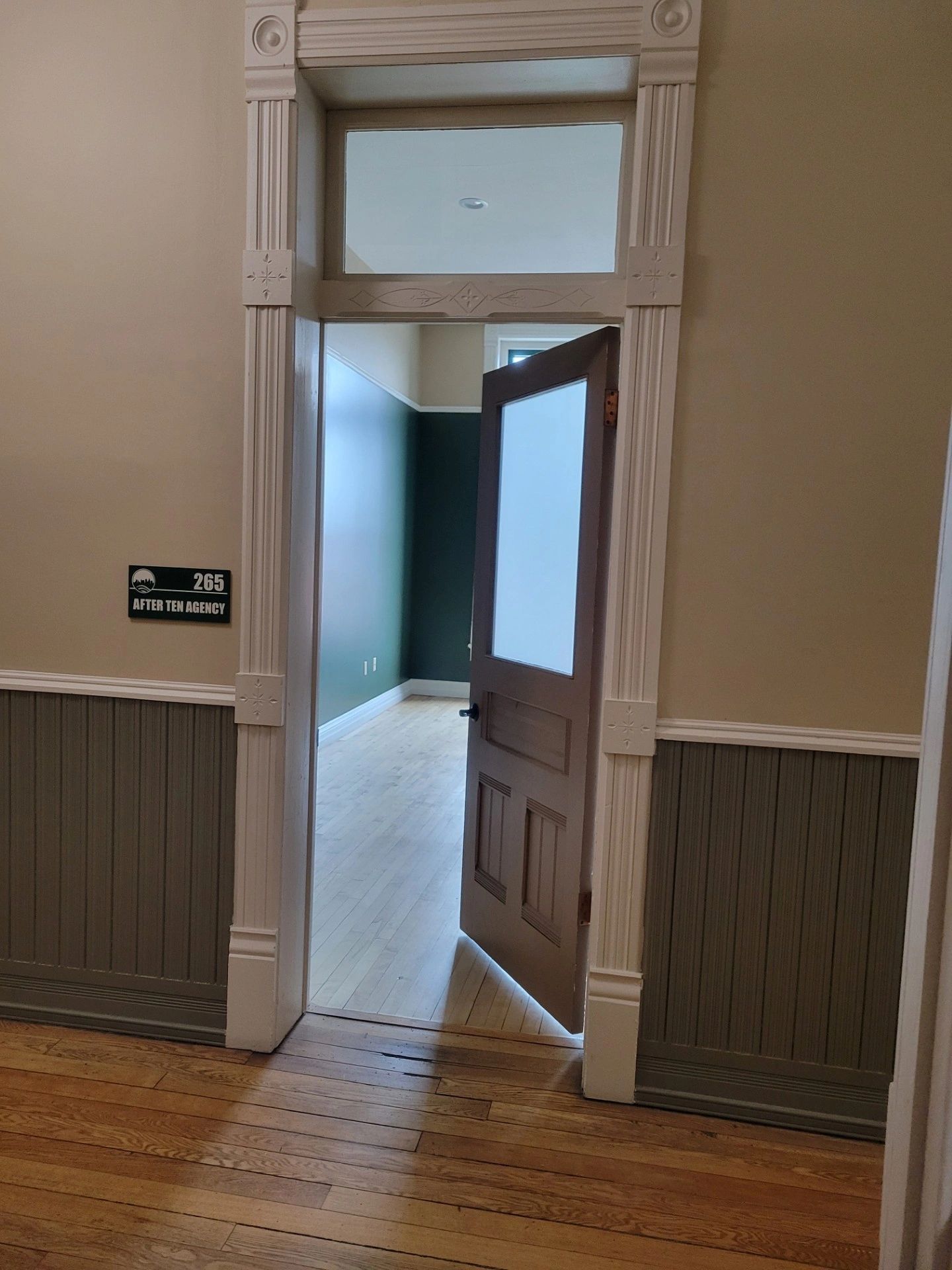 Wooden door partially open revealing room 265.