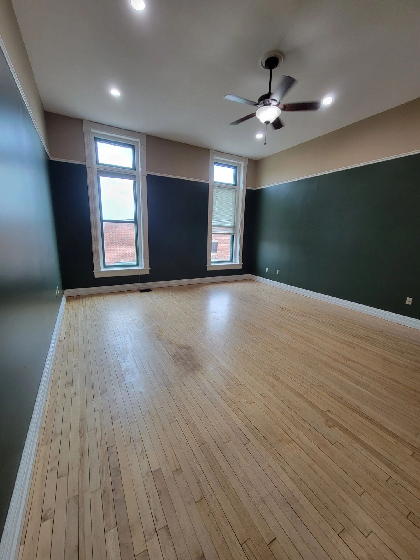Empty room with dark green walls and hardwood floors.