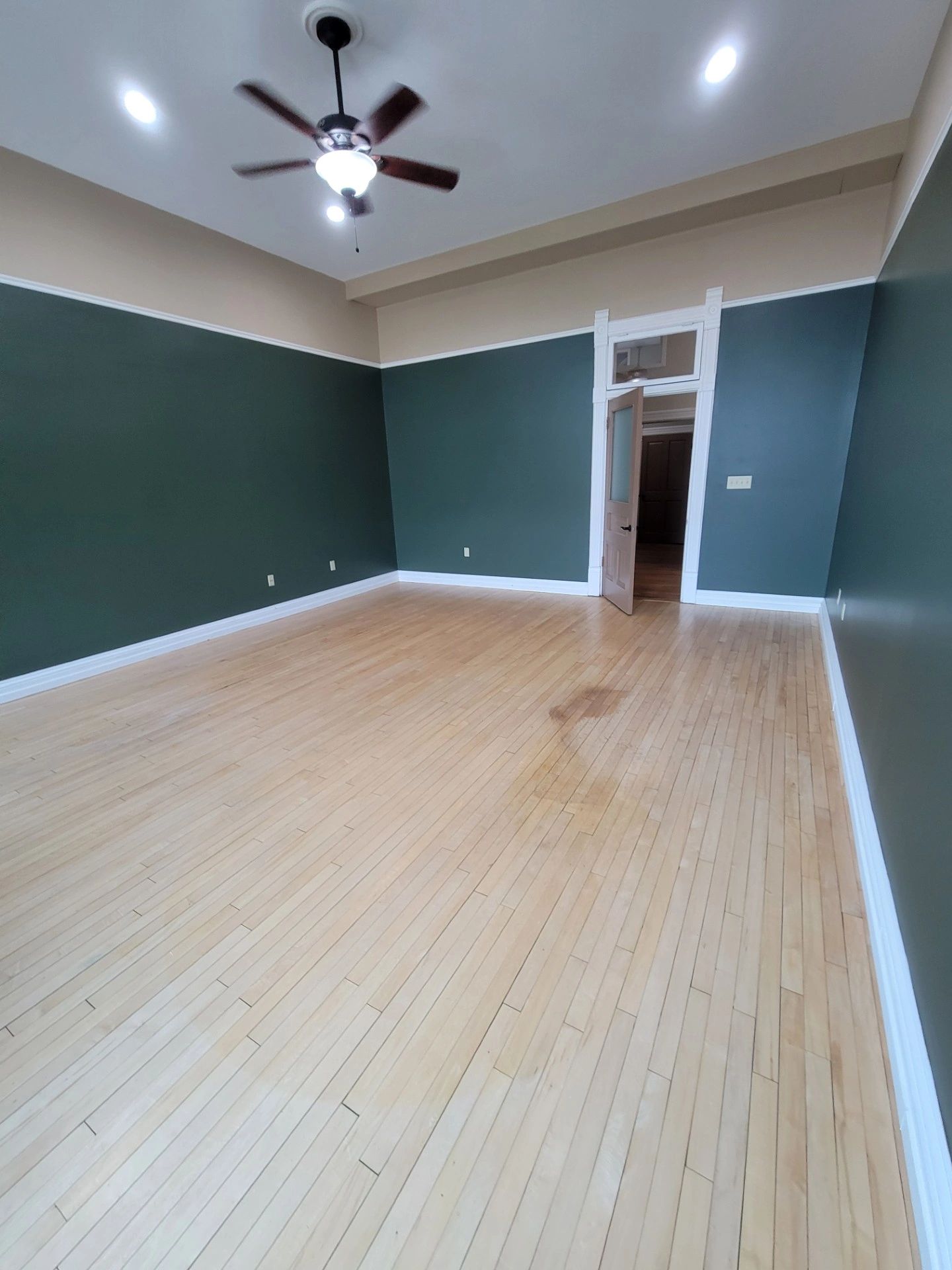 Empty room with green walls and wooden floor.