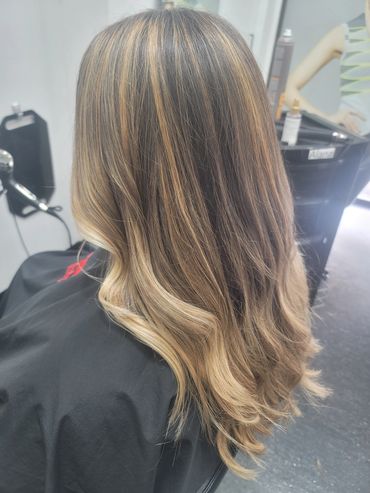 Long, wavy hair with blonde highlights in a salon.
