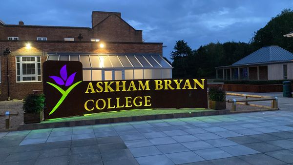 A photograph of a metal wall with the name askham bryan laser cut into it with their flower logo. Le