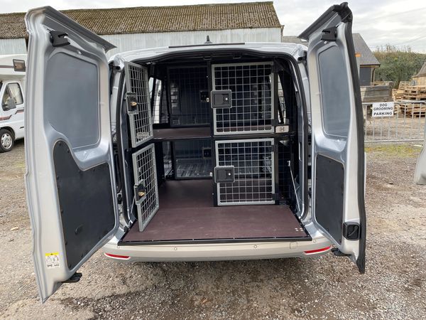 Photograph of the back of a van with double height dog cages.