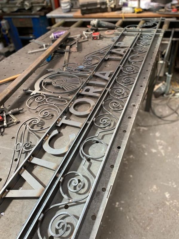 Photo of a steel laser cut logo Victoria Tap, swirl detail and train icon