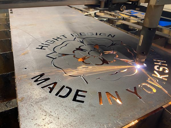 Photograph of plasma machine cutting a piece of metal with yorkshire rose logo