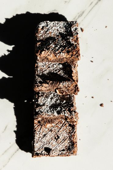 Three chocolate brownies dusted with powdered sugar.