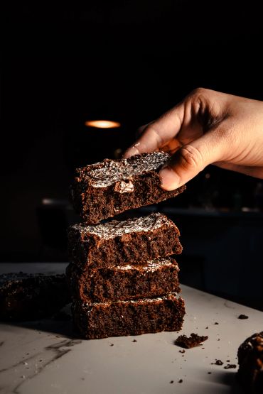 Hand picking a piece of chocolate brownie from a stack.
