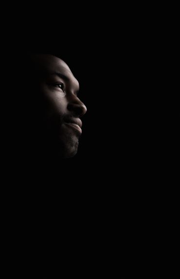 Side profile of a man's face in low light.