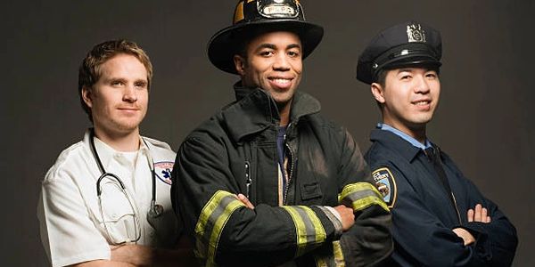 Three emergency responders—a paramedic, firefighter, and police officer—stand confidently.