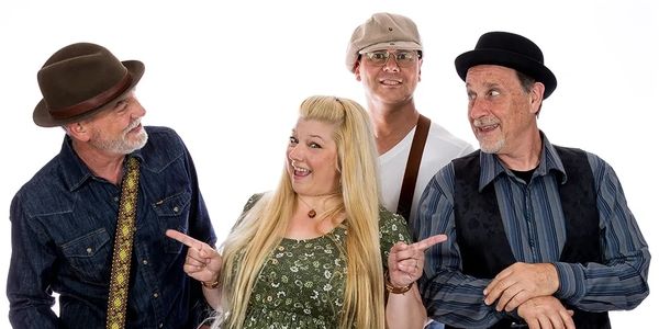 A joyful group of four adults, two men and one woman, dressed in vintage-style clothing, smiling and pointing.