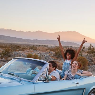 Image of 4 people in a car on a road trip, excited for the destination.