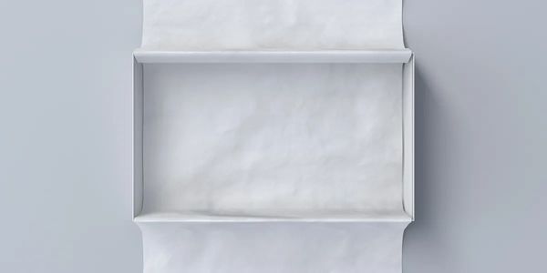 A flat, rectangular white object with folded edges on a gray background.
