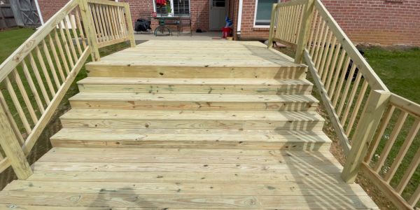 Newly constructed wooden deck with stairs and railings in a backyard.