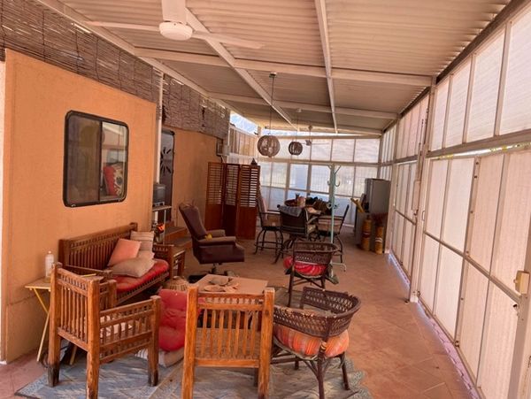 Cozy enclosed patio with wooden and wicker furniture and soft cushions.