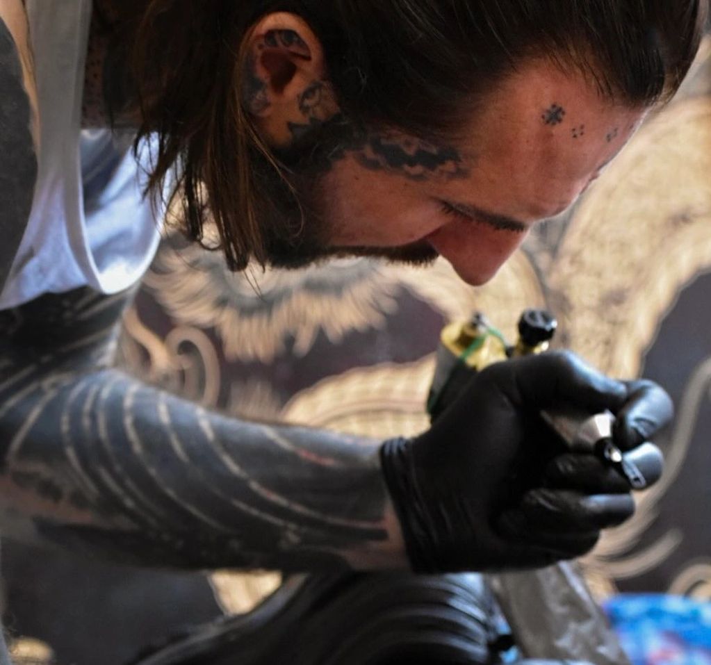 Tattoo artist with gloves working intently on a tattoo.
