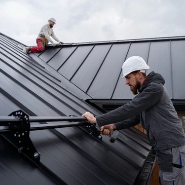 Two workers installing equipment on a metal roof.