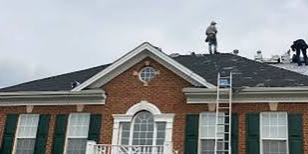 Workers on a roof repairing shingles.