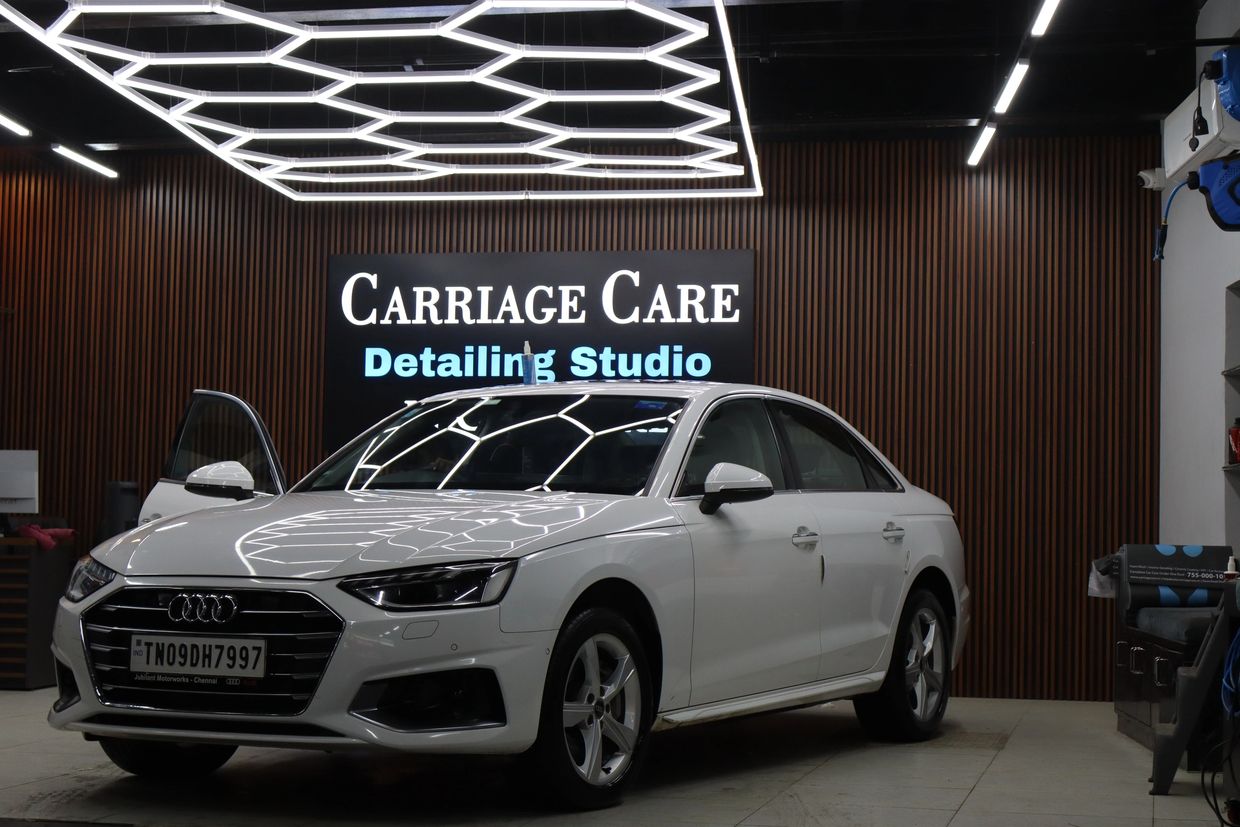 White Audi sedan inside Carriage Care Detailing Studio with door open.