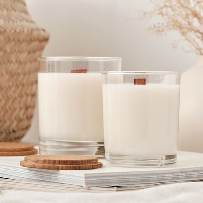 Two white wood wick candles in glass jars with wooden lids. Lids are off and sitting next to jars.