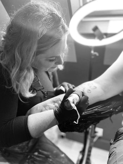 Cat Beazeley tattooing an arm