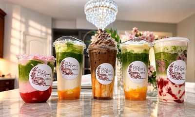 Colorful layered drinks with vibrant toppings arranged on a marble table.