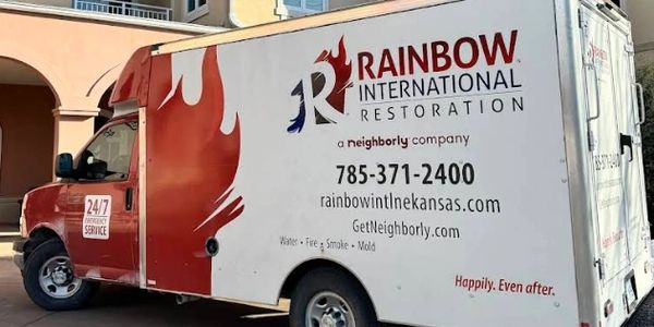 Rainbow Restoration International box van parked outside of a large building