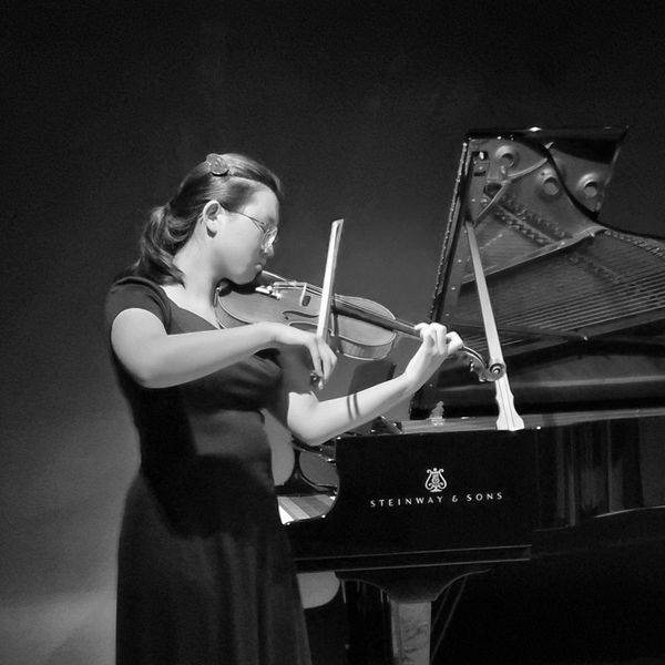 Woman playing violin next to Steinway &amp; Sons piano.