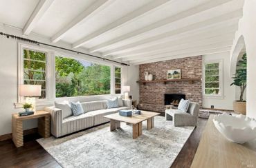 Bright living room with large windows and brick fireplace.