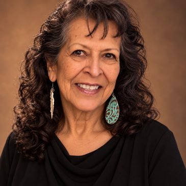 Smiling woman with curly hair and unique earrings.