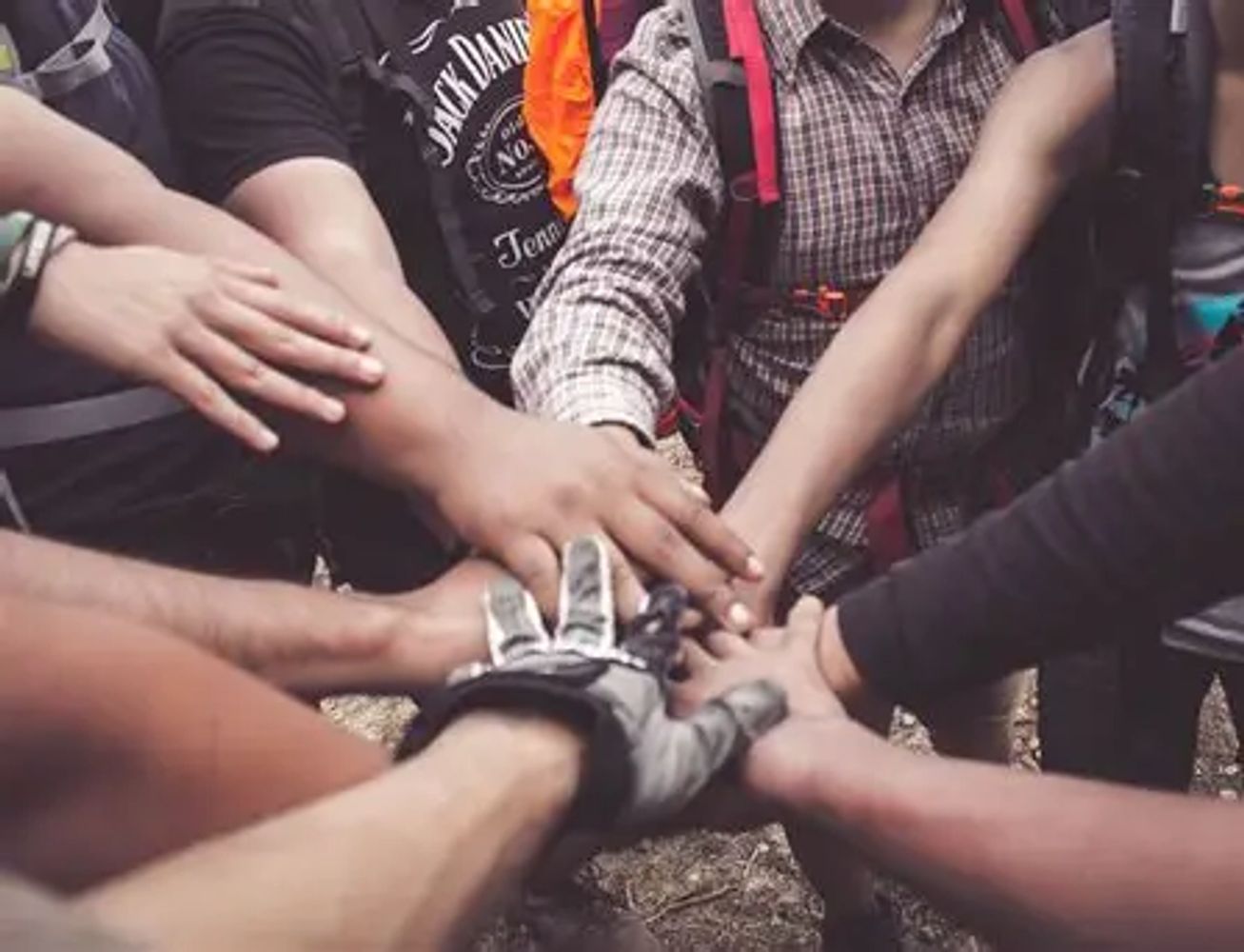 Group of people joining hands in a circle showing unity.