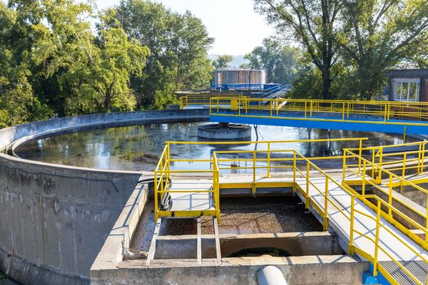 Aerial view of a circular clarifier at a water or sewage treatment with yellow and blue railings.