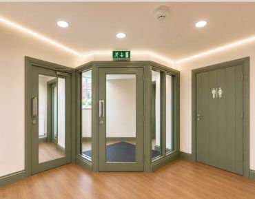 Interior hallway with glass doors and restroom entrance.