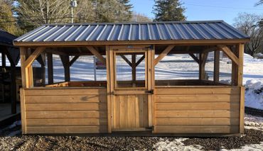 Wooden outdoor gazebo with a metal roof and screened sides.