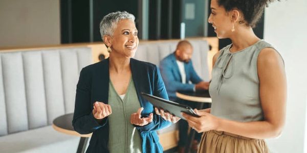 Two women engaged in a lively discussion in a modern office setting.