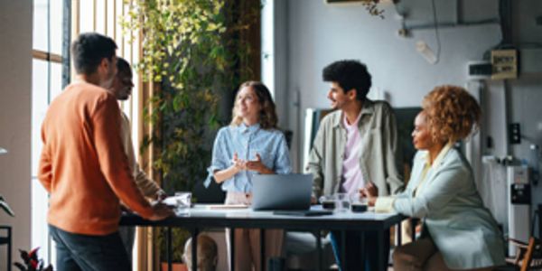 A diverse group having a lively meeting around a table in a bright office.