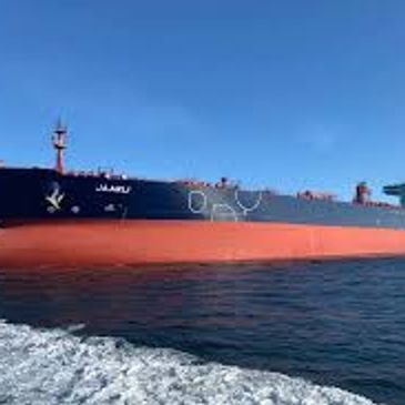 Large cargo ship named JIAARU on the water under a clear blue sky.