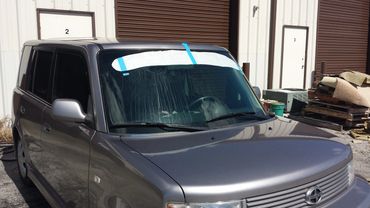 Vinyl in the middle of installation on the windshield of a 2008 Scion XB