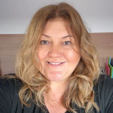 Smiling woman with wavy blonde hair indoors.