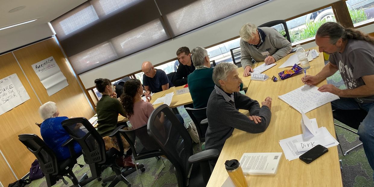 Group of people engaged in a collaborative meeting around a table with papers and notes.