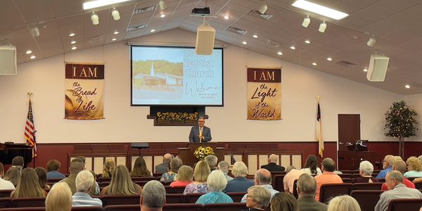 A pastor speaks to a congregation inside a church sanctuary.