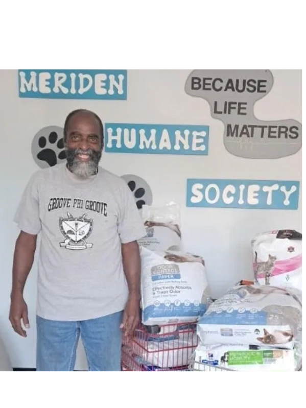 Smiling man stands in front of pet supplies at Meriden Humane Society.