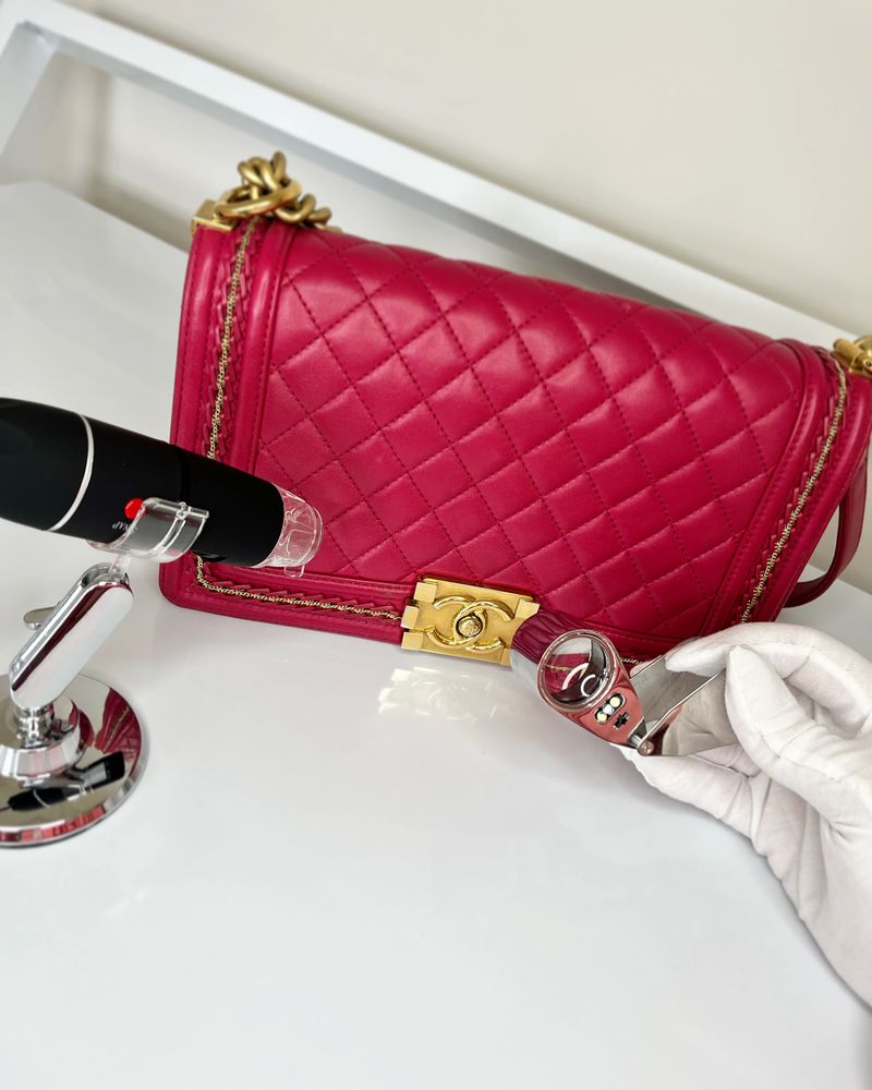Red quilted Chanel handbag being examined with a magnifying glass and microscope.