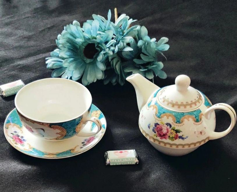 Elegant tea set with floral design on black surface.