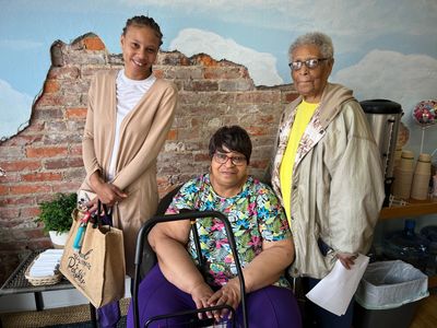 Three new food pantry clients smile for a photo at One Mission Cambridge.