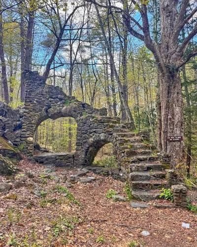 Stone ruins with arch and staircase in the woods.