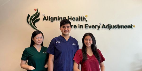 Three healthcare professionals standing in front of a health clinic sign.