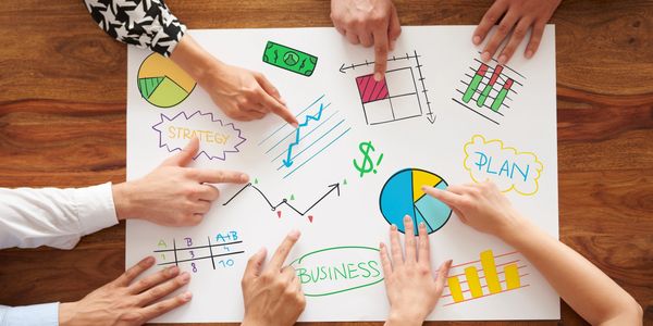 Multiple hands pointing at business strategy and plan charts on paper.