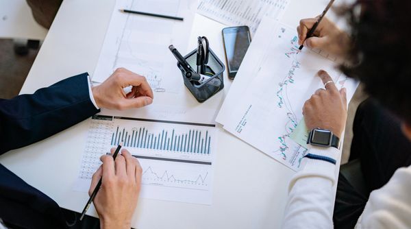 Two people analyzing financial charts and graphs at a desk.