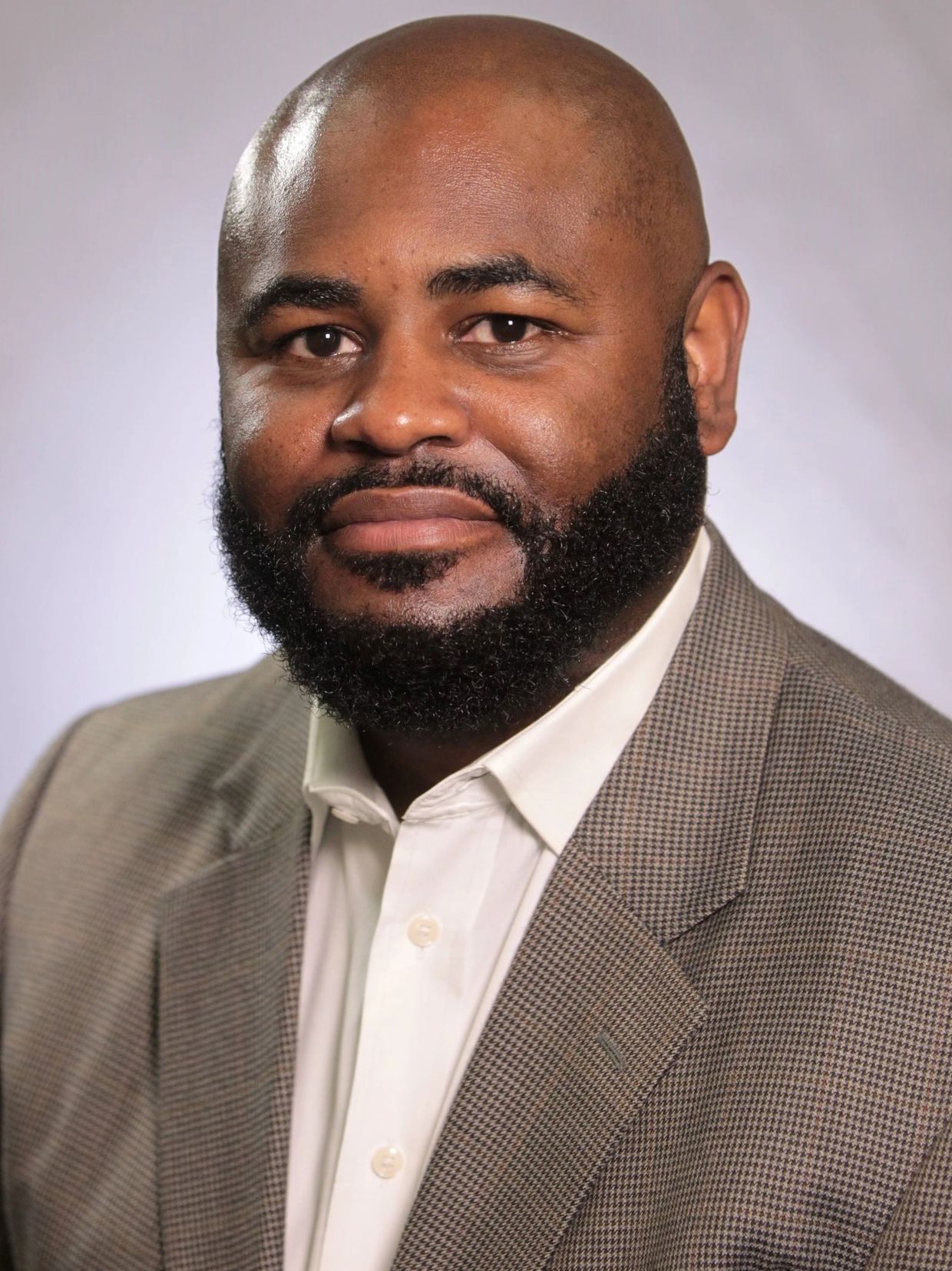 Professional man in a checked blazer and white shirt.